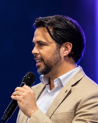 Dr. Carpes fala ao microfone, no palco.