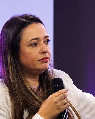 Dra. Cássia ao microfone, no palco.