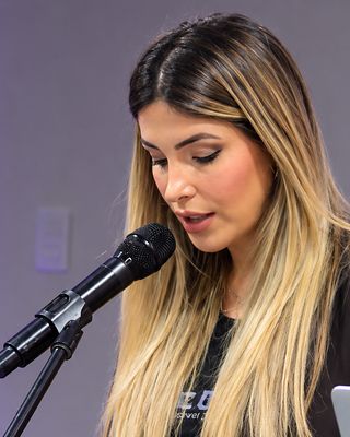 Dani lê ao microfone, no púlpito.