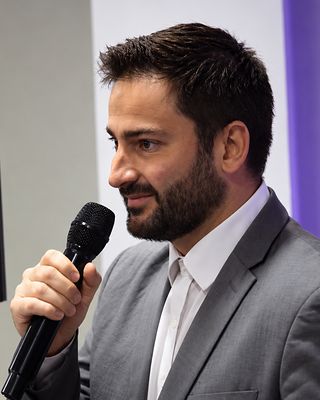 Dr. Gabriel fala ao microfone, no palco.