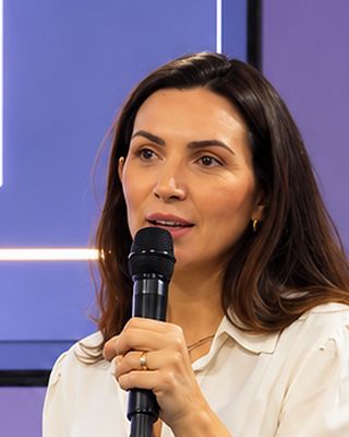 Dra. Louise fala ao microfone diante da plateia.