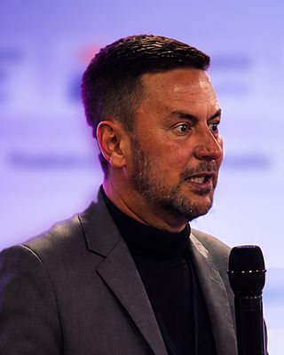 Marcelo fala ao microfone, no palco.