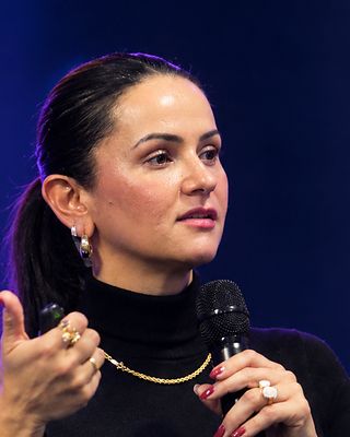 Dra. Neydianne gesticula enquanto fala ao microfone, no palco.